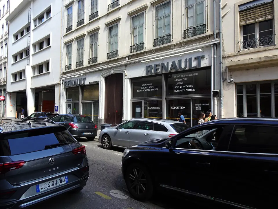 Vitrine d'une concession automobile rue Duhamel, à Lyon, qui propose « Leasing » et « Plans de financement », des voitures garées devant